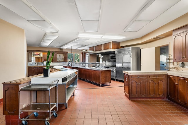 kitchen featuring kitchen peninsula, tile patterned flooring, appliances with stainless steel finishes, and a kitchen island