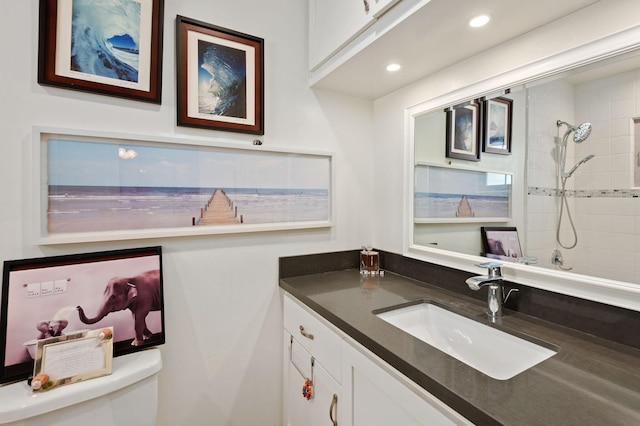 bathroom with a tile shower, vanity, and toilet