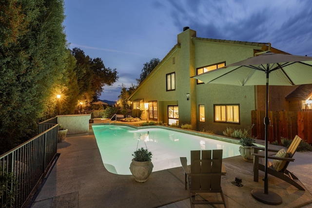 pool at dusk with a patio area