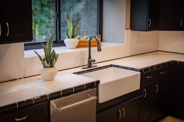 kitchen featuring dishwasher, sink, decorative backsplash, and tile counters