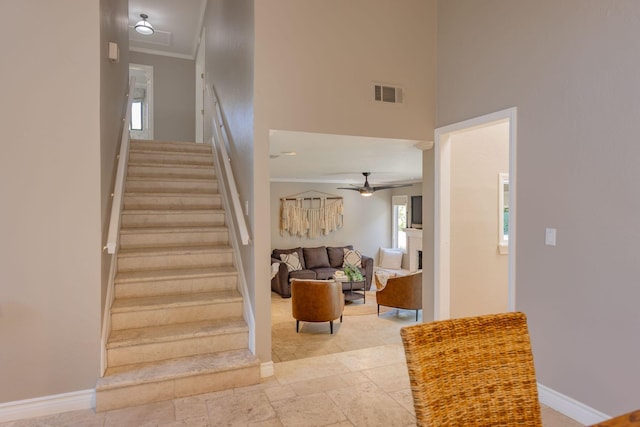 stairway featuring ceiling fan and crown molding