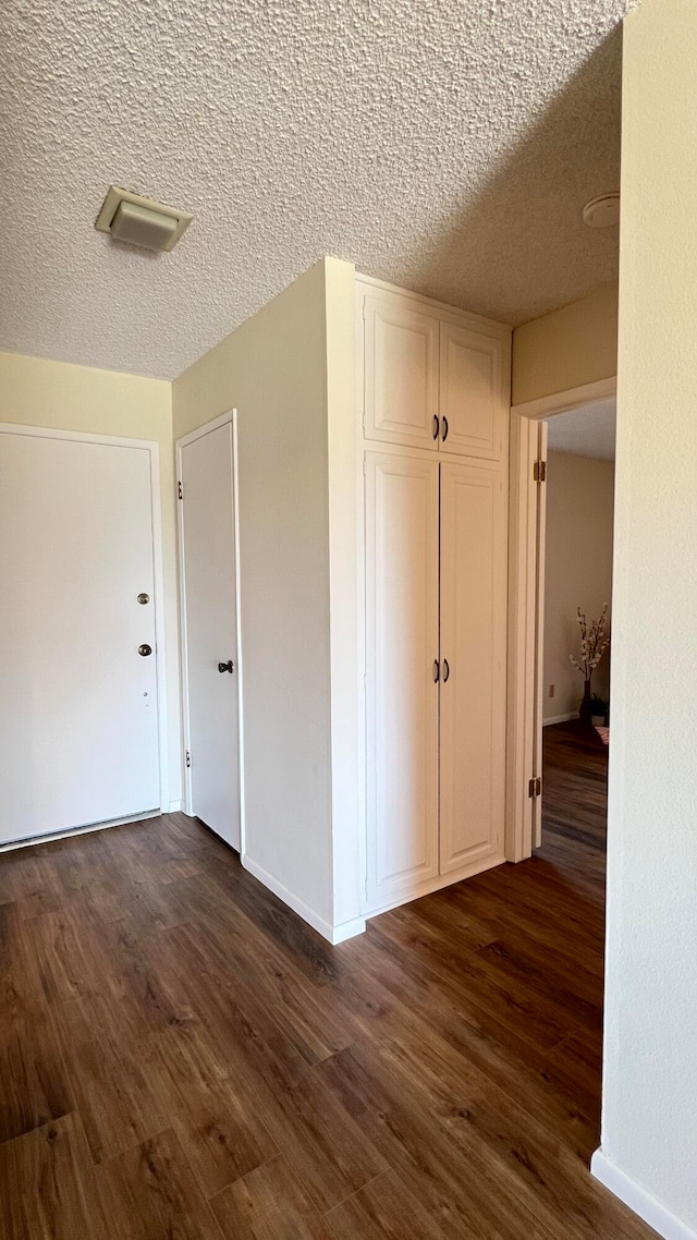 hallway with dark hardwood / wood-style flooring and a textured ceiling