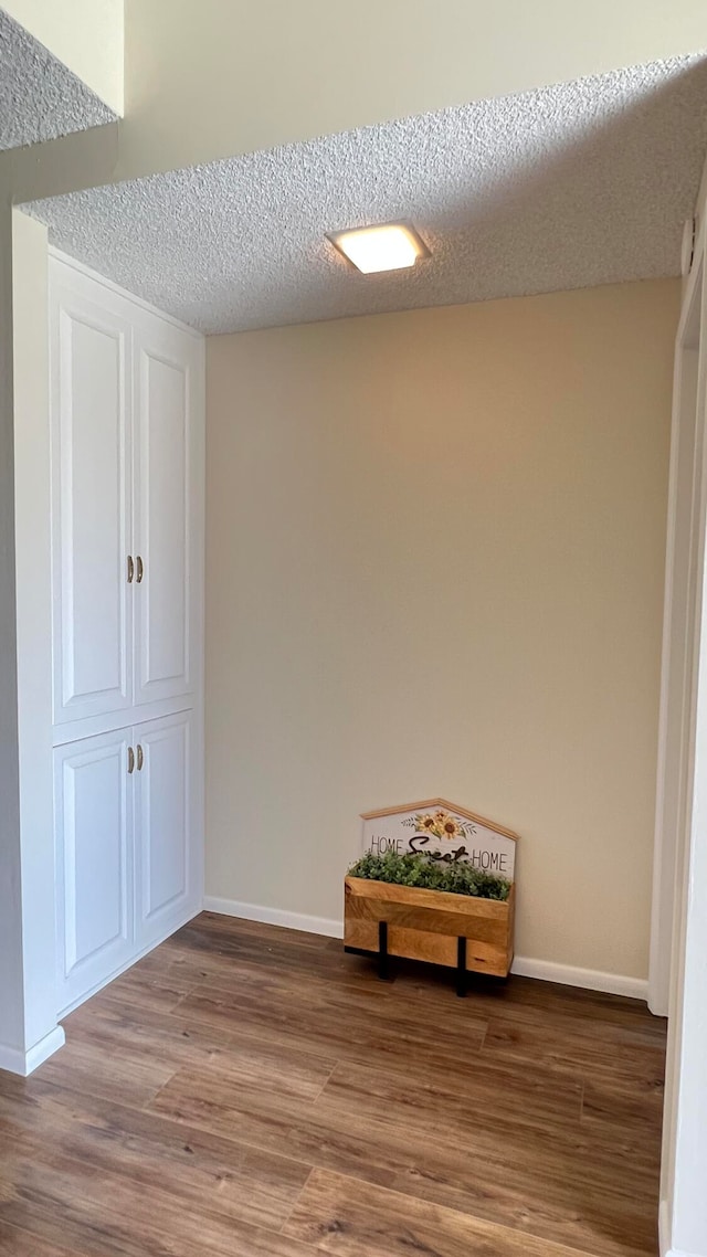 hall with hardwood / wood-style floors and a textured ceiling