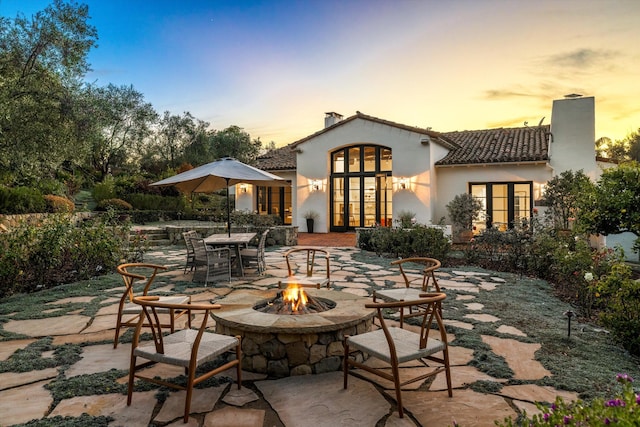 back house at dusk with a patio area and a fire pit