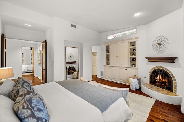 bedroom with dark hardwood / wood-style floors and a brick fireplace