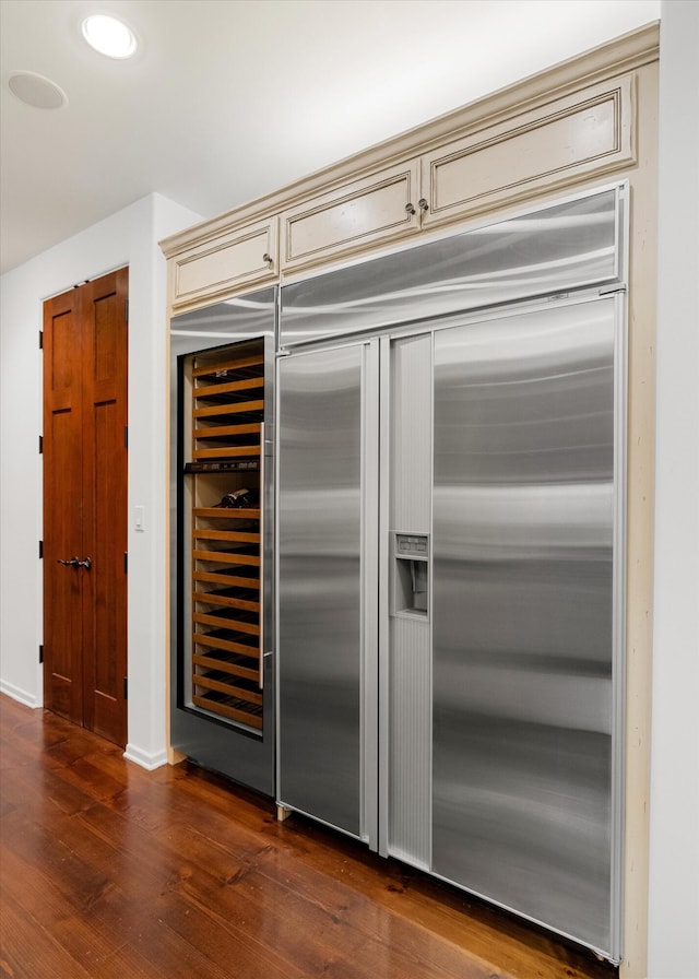 kitchen with stainless steel built in refrigerator, cream cabinets, dark hardwood / wood-style flooring, and beverage cooler