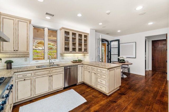 kitchen with dark wood-type flooring, cream cabinets, stainless steel dishwasher, and sink