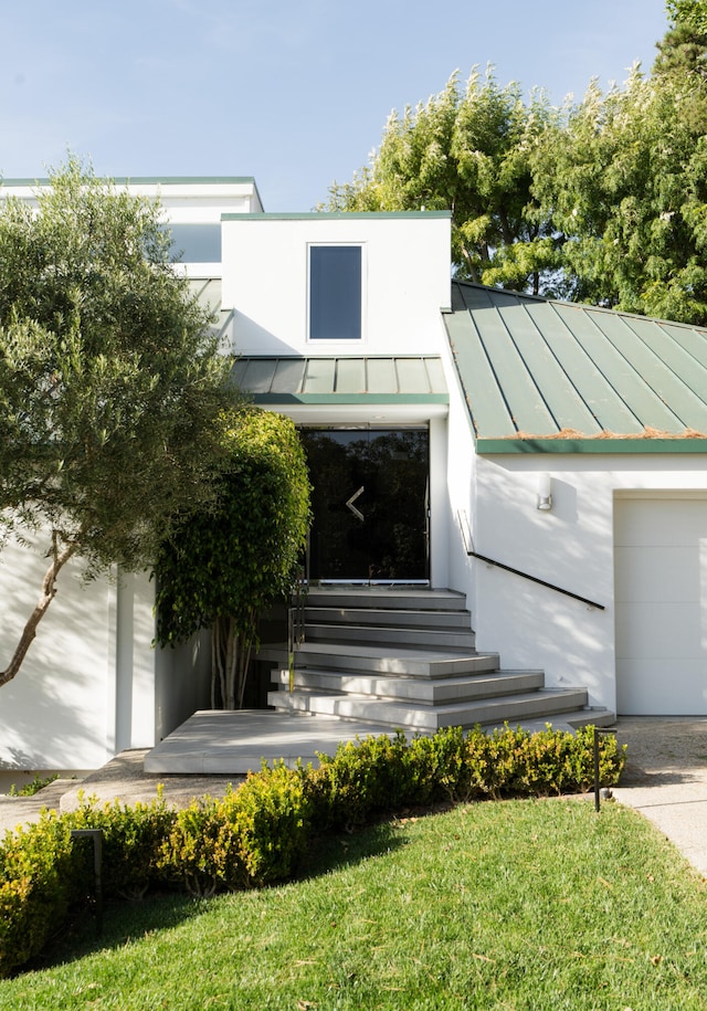 doorway to property with a yard and a garage