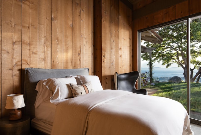 bedroom featuring wood walls, a water view, and access to outside