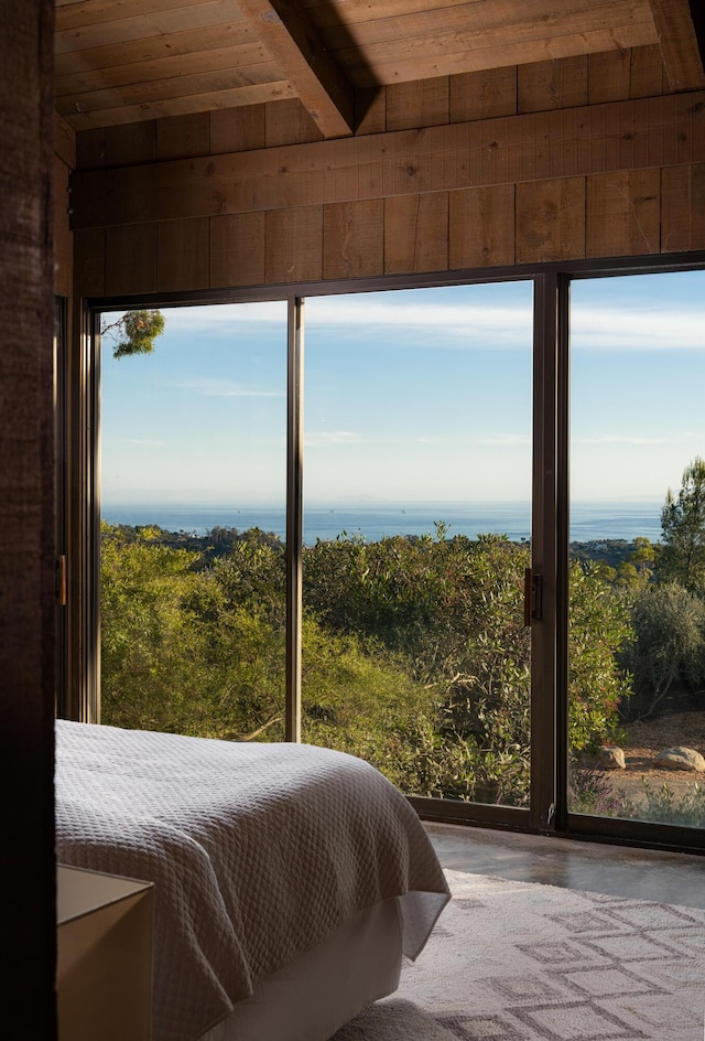 bedroom featuring beam ceiling, wooden ceiling, wooden walls, and multiple windows