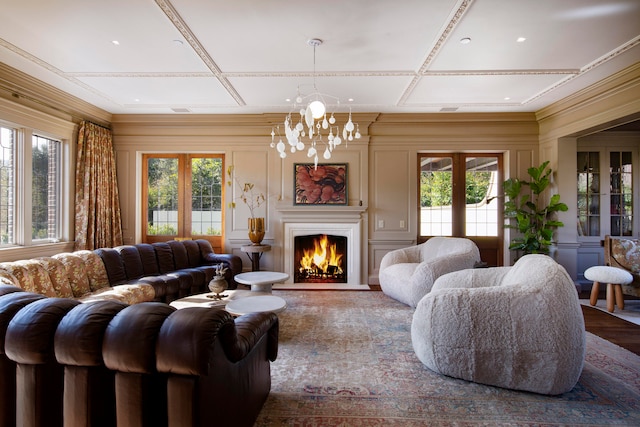 living room featuring wood-type flooring, a notable chandelier, a healthy amount of sunlight, and coffered ceiling