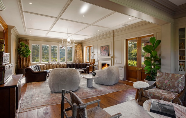 living room with a wealth of natural light, hardwood / wood-style floors, a chandelier, and coffered ceiling