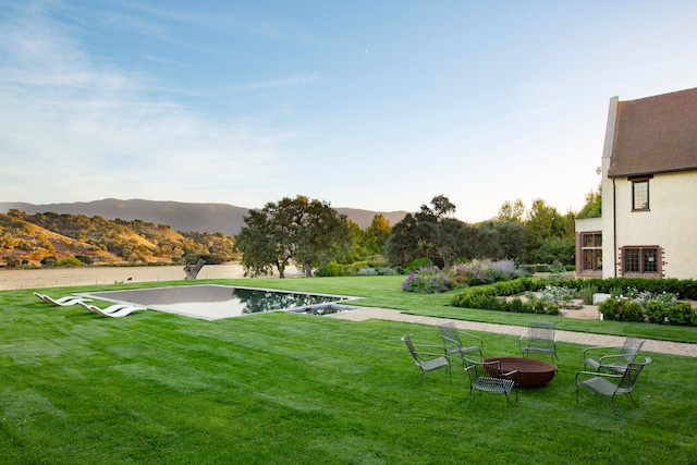 surrounding community with a mountain view, a yard, and an outdoor fire pit