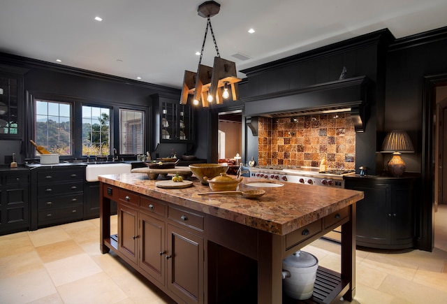 kitchen with decorative backsplash, ornamental molding, sink, pendant lighting, and a kitchen island