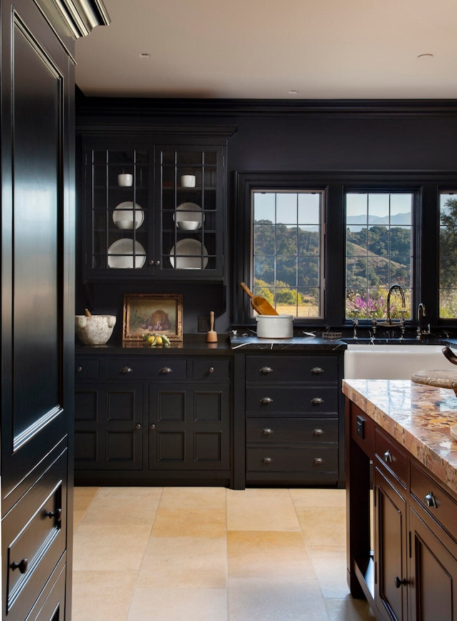 bar with sink, light stone counters, a mountain view, light tile patterned floors, and ornamental molding