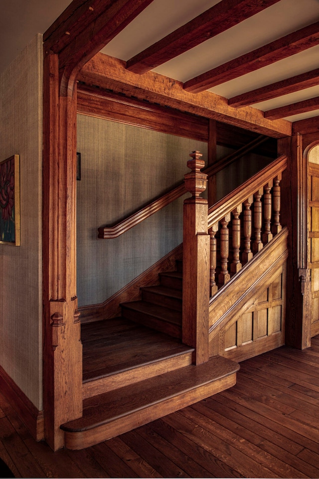 staircase featuring beam ceiling and hardwood / wood-style flooring