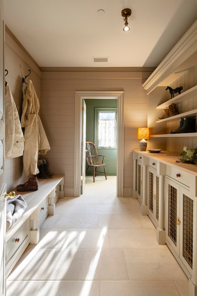 mudroom with light tile patterned flooring and wood walls