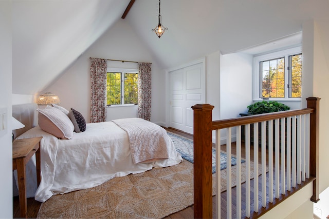 bedroom featuring multiple windows, lofted ceiling with beams, and hardwood / wood-style flooring