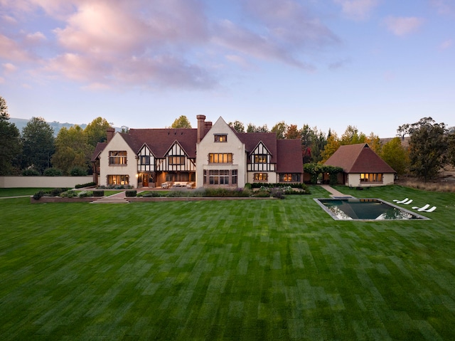 back house at dusk featuring a lawn