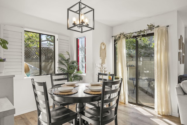 dining area with light hardwood / wood-style flooring, a healthy amount of sunlight, and a notable chandelier