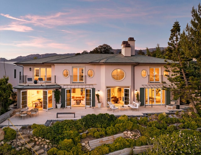 back house at dusk featuring an outdoor hangout area and a balcony