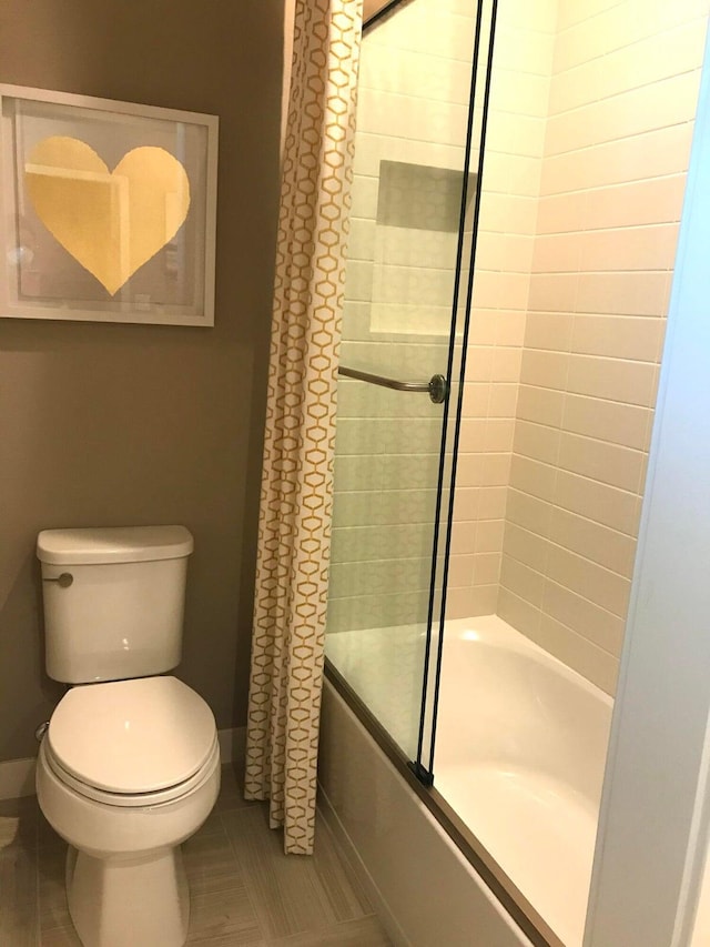 bathroom with tile patterned floors, enclosed tub / shower combo, and toilet