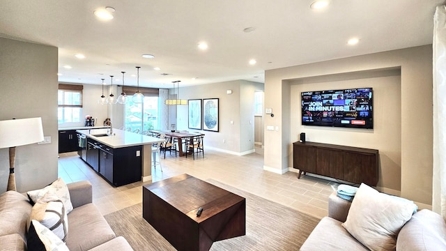 living room featuring light tile patterned floors, sink, and an inviting chandelier