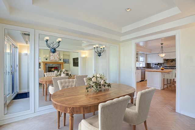 dining area with a raised ceiling, light parquet floors, and a notable chandelier