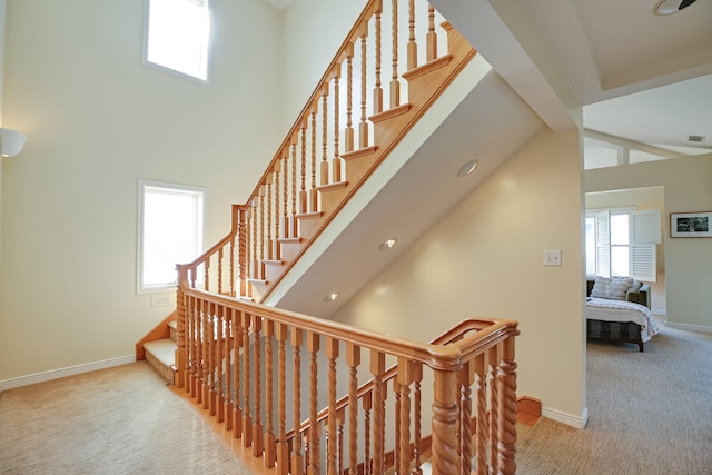 staircase with carpet flooring, high vaulted ceiling, and a wealth of natural light