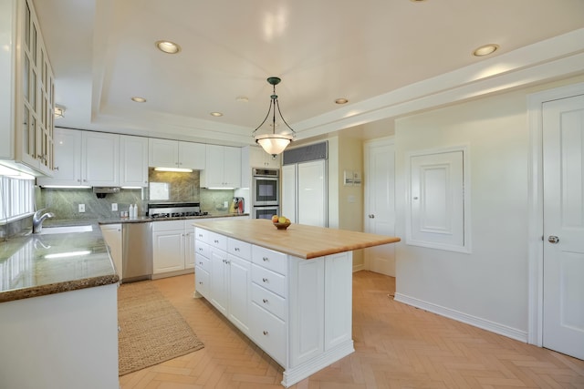 kitchen featuring pendant lighting, a center island, backsplash, appliances with stainless steel finishes, and white cabinetry