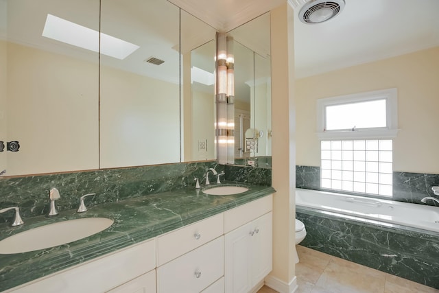 bathroom with a skylight, a relaxing tiled tub, tile patterned floors, toilet, and vanity