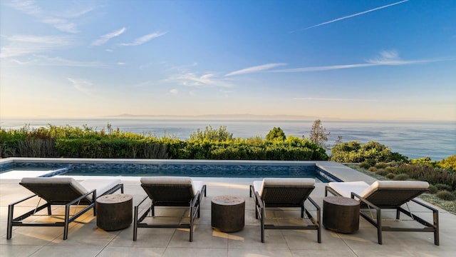 pool at dusk featuring a fire pit and a water view