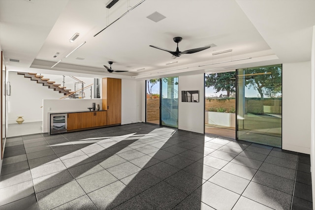 interior space featuring a raised ceiling, wine cooler, ceiling fan, and a wall of windows