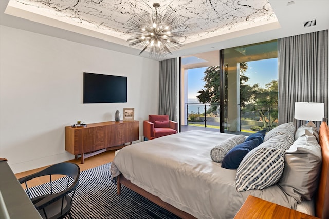 bedroom featuring a tray ceiling, wood-type flooring, and an inviting chandelier