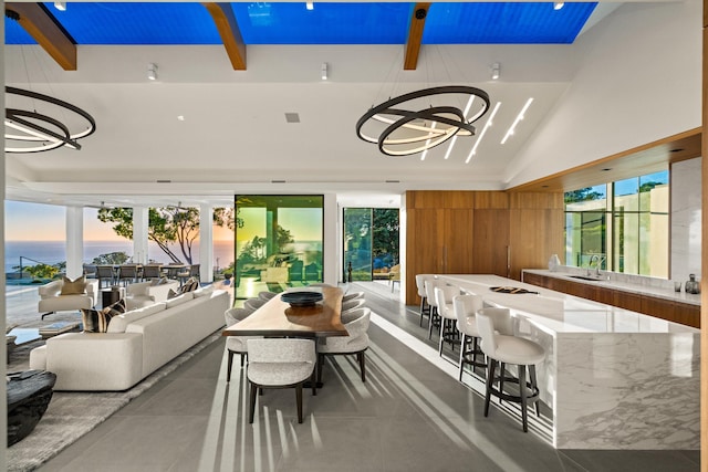 dining room with sink, an inviting chandelier, concrete floors, vaulted ceiling, and wooden walls