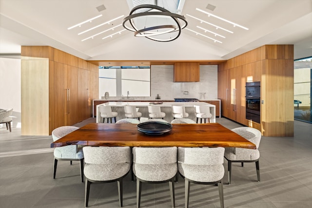 dining space with an inviting chandelier, vaulted ceiling, and sink