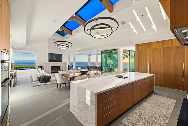 kitchen with a large island, stainless steel oven, and light stone counters