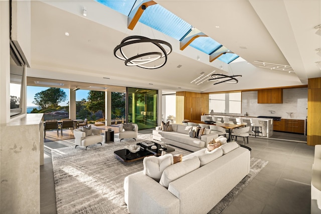 living room featuring lofted ceiling with skylight and a notable chandelier