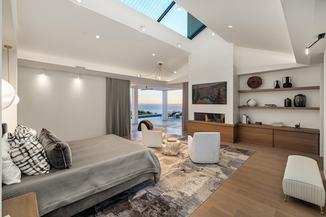 bedroom with hardwood / wood-style floors, high vaulted ceiling, rail lighting, and access to outside