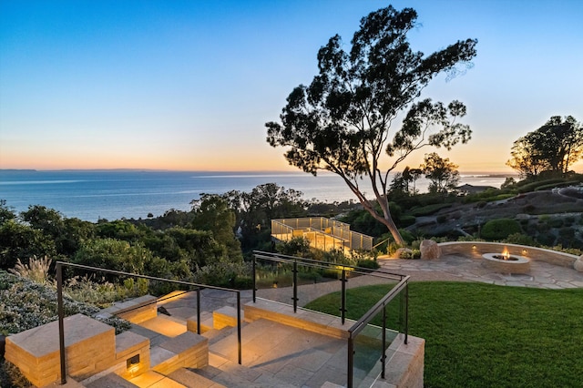 view of home's community featuring a water view, a fire pit, a patio area, and a lawn