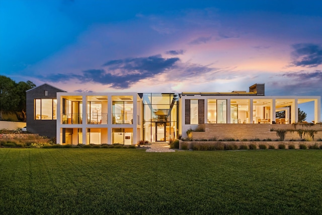 back house at dusk with a lawn