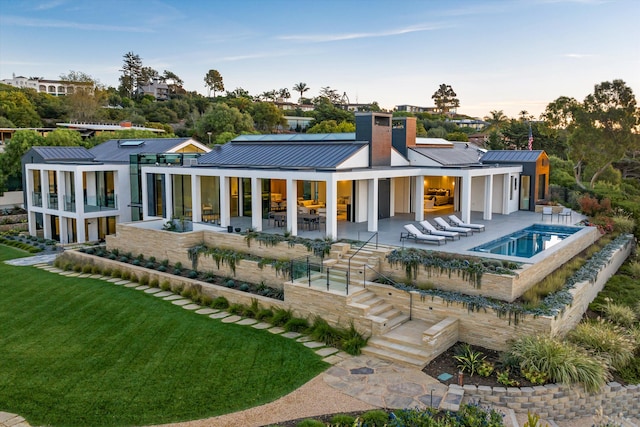 back house at dusk with an outdoor living space, a swimming pool with hot tub, a yard, and a patio