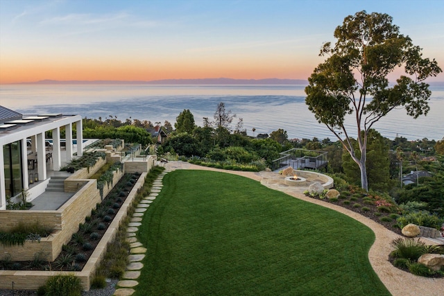 yard at dusk featuring a water view