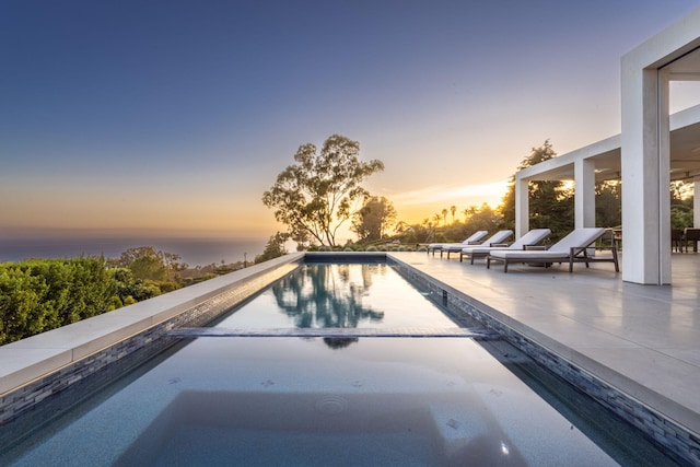 pool at dusk with a patio