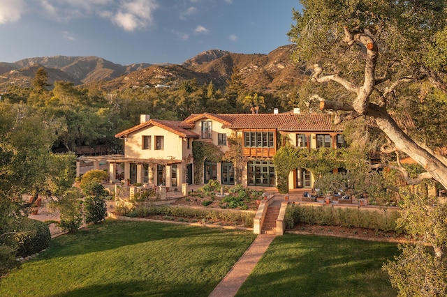 view of front of home featuring a patio, a mountain view, and a front yard