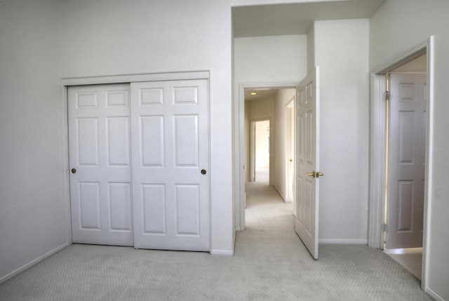 unfurnished bedroom with a closet and light colored carpet