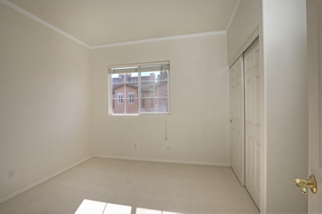 unfurnished bedroom featuring light colored carpet, crown molding, and a closet