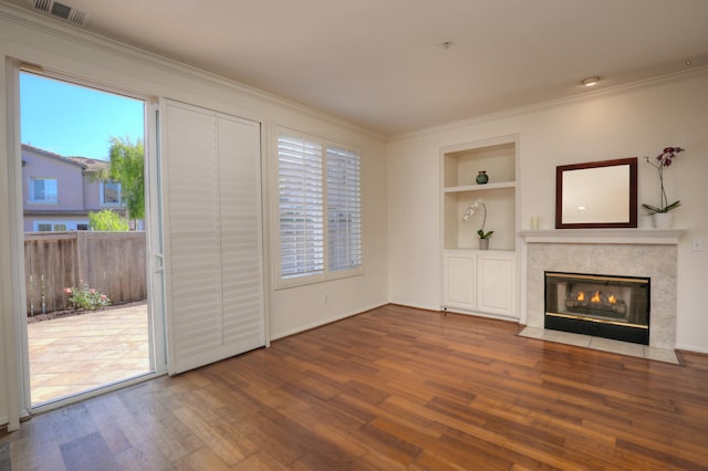 unfurnished living room featuring a high end fireplace, a healthy amount of sunlight, and hardwood / wood-style flooring