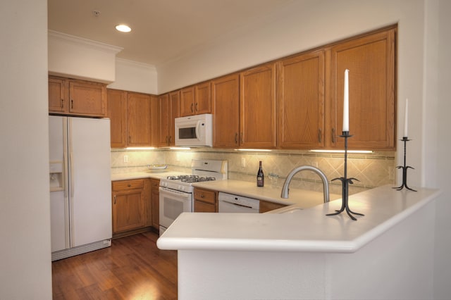 kitchen featuring backsplash, kitchen peninsula, dark wood-type flooring, and white appliances