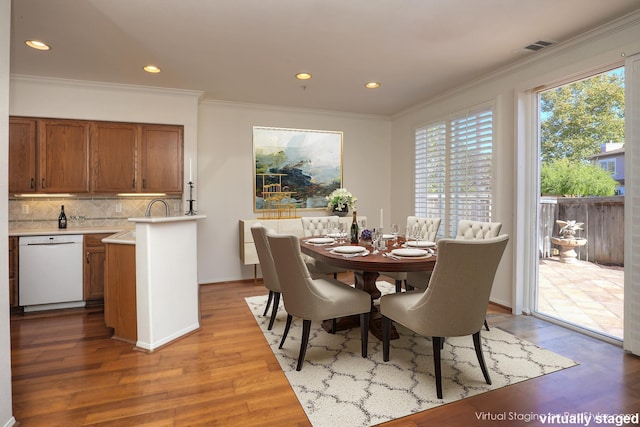 dining room with sink, wood-type flooring, and crown molding